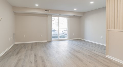 A room with light wood flooring and a sliding glass door.