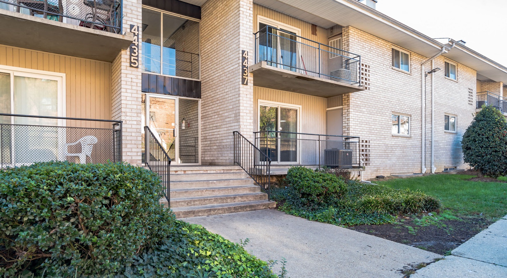 the view of an apartment building with stairs and a sidewalk