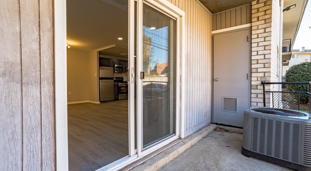 A patio with a sliding glass door leading to a kitchen.