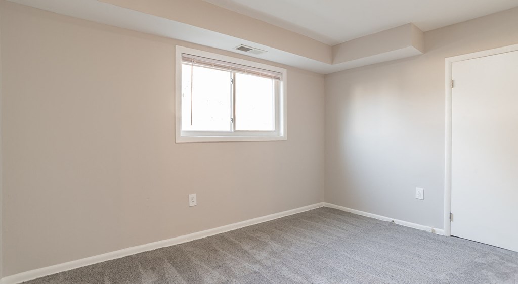 A room with a window and carpeted floor.