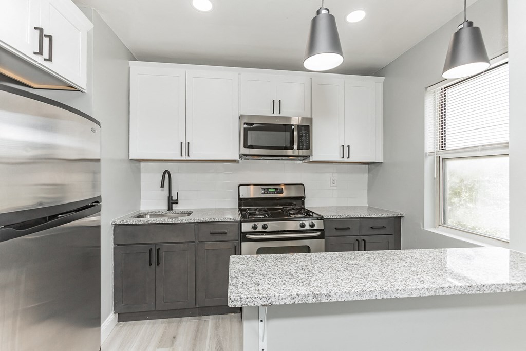a kitchen with white cabinets and granite counter tops and stainless steel appliances