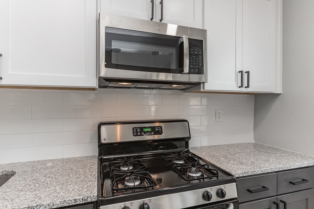 a kitchen with white cabinets and a stove and a microwave
