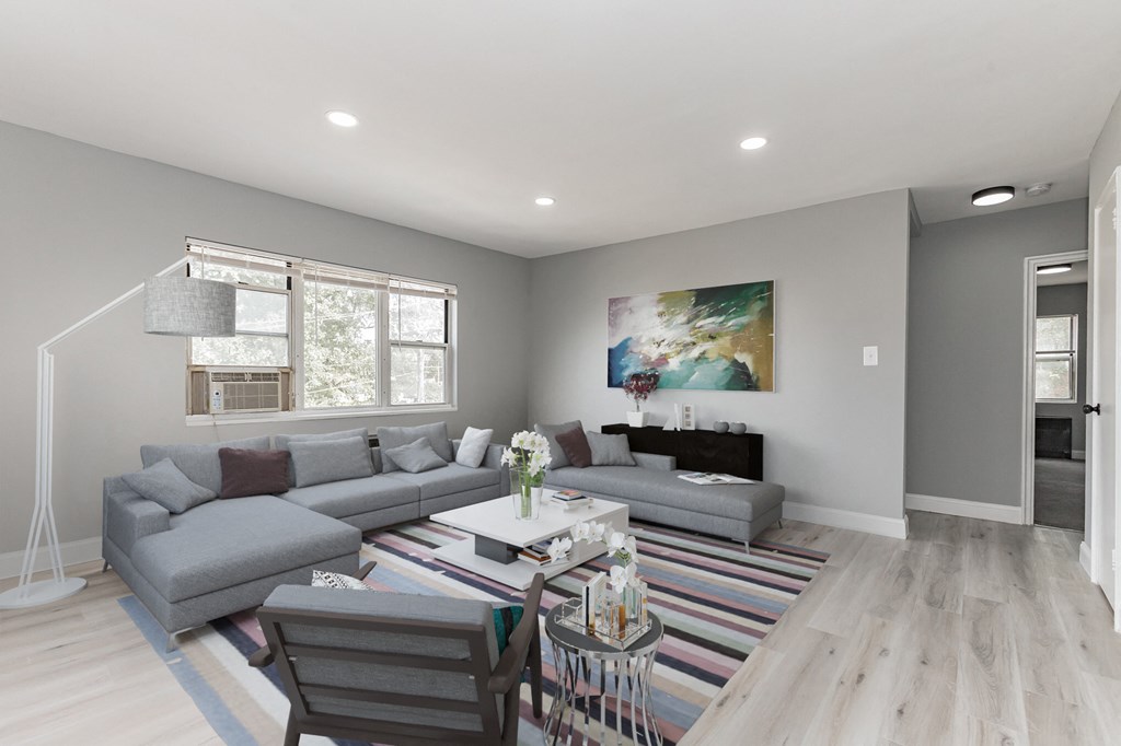 a living room with grey couches and a table and chairs