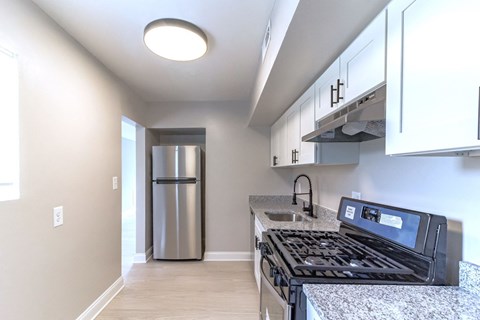 A kitchen with a black stove top oven and a stainless steel refrigerator.