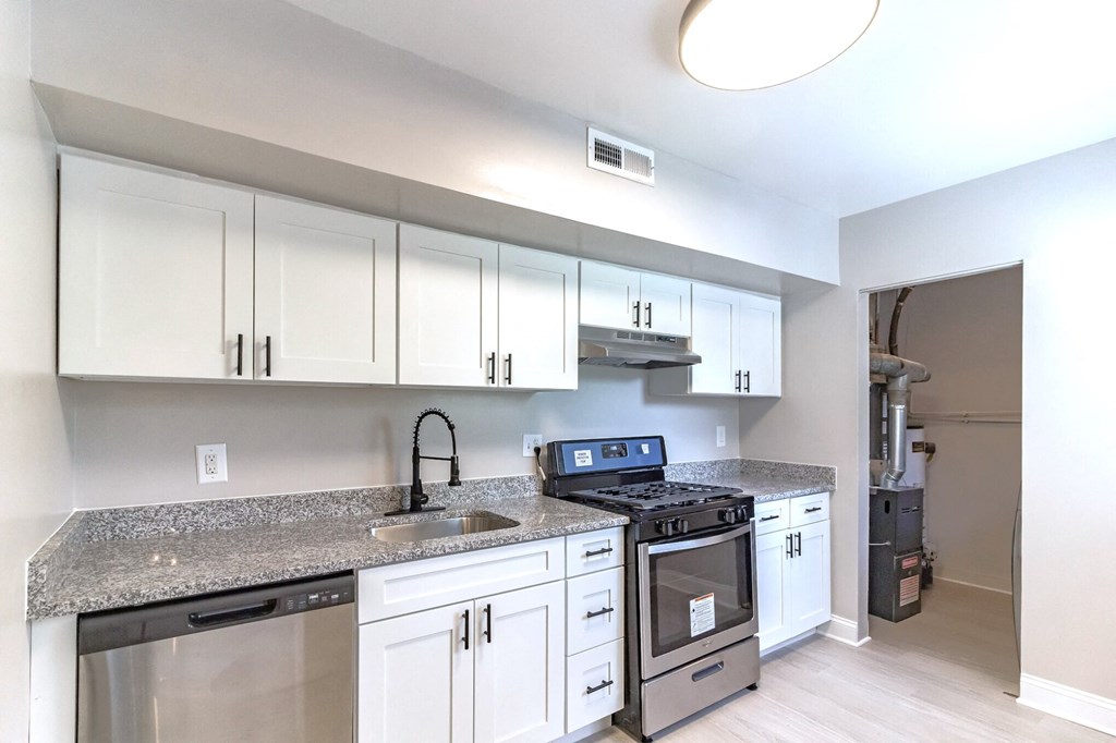 A kitchen with white cabinets and a granite countertop.