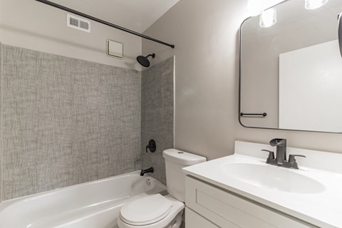 A white bathroom with a toilet, sink, and bathtub.