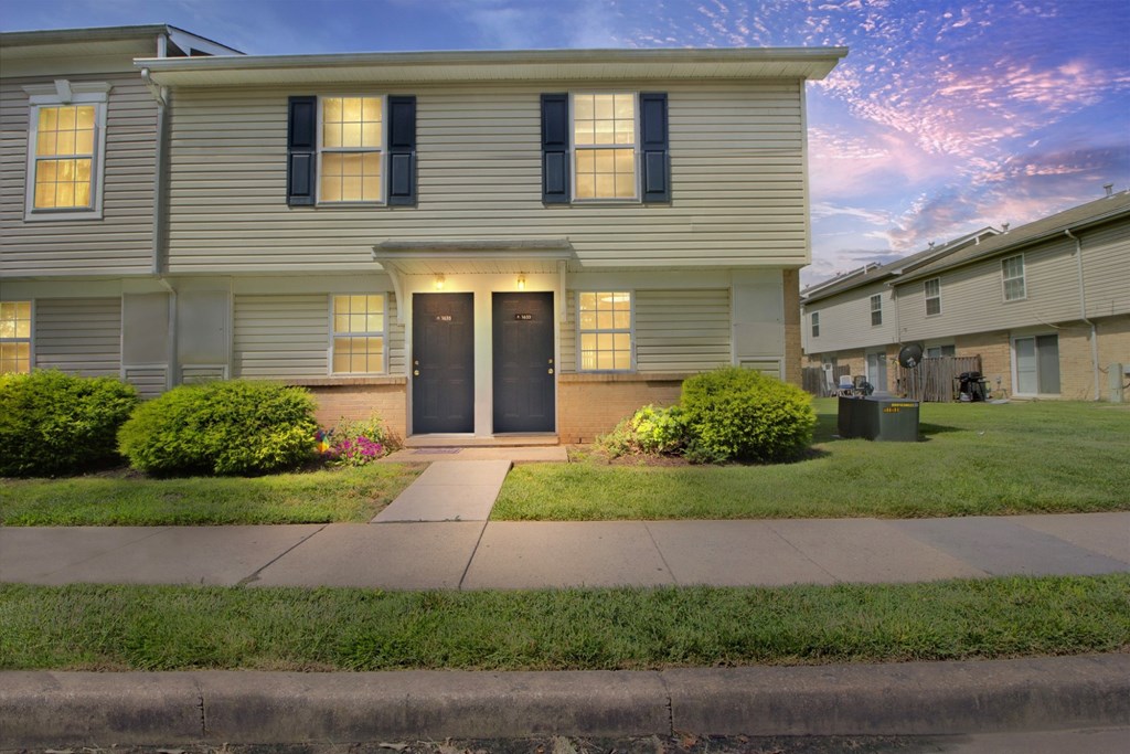 A two-story house with a front yard and a sidewalk.
