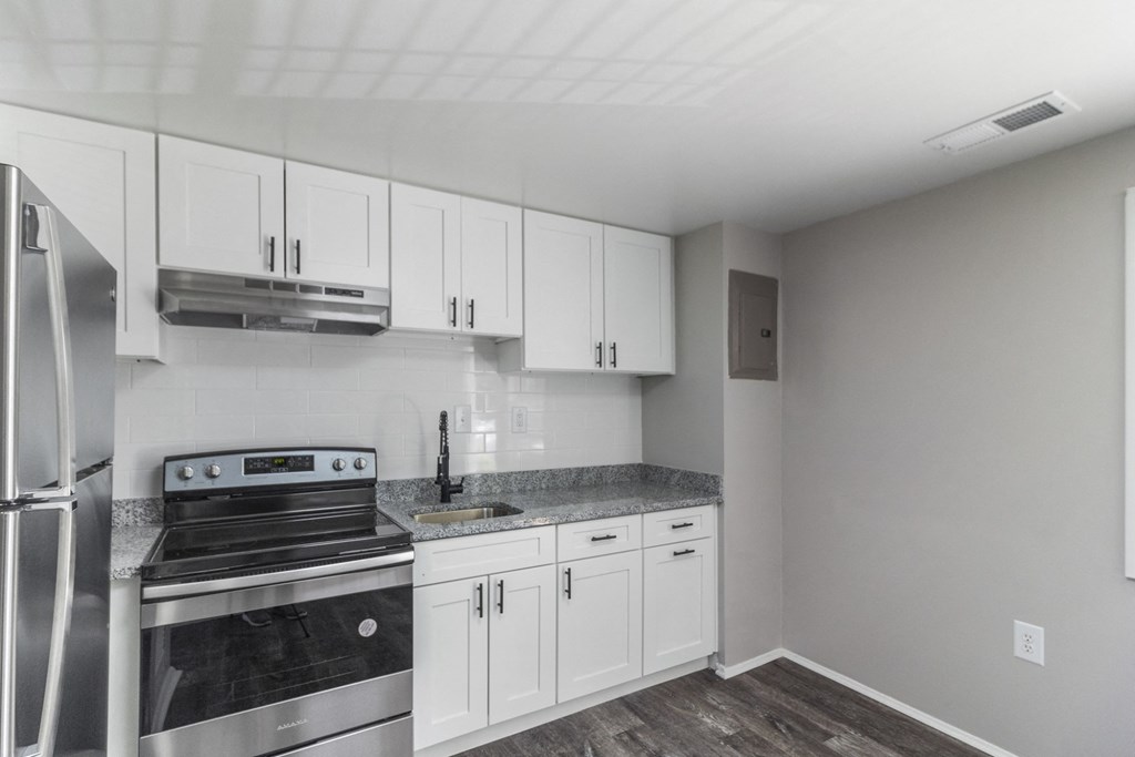 A kitchen with a stainless steel refrigerator, oven, and cabinets.