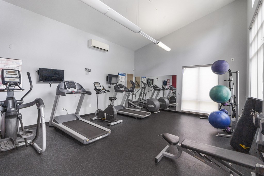 A gym with a variety of equipment including treadmills, exercise balls, and weights.