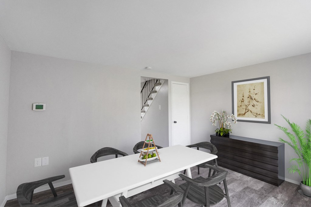 A white dining table with chairs and a plant on the side.