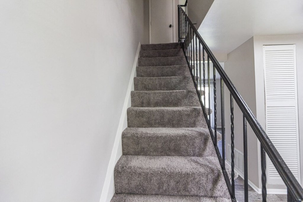 A staircase with a carpeted runner and black handrails.