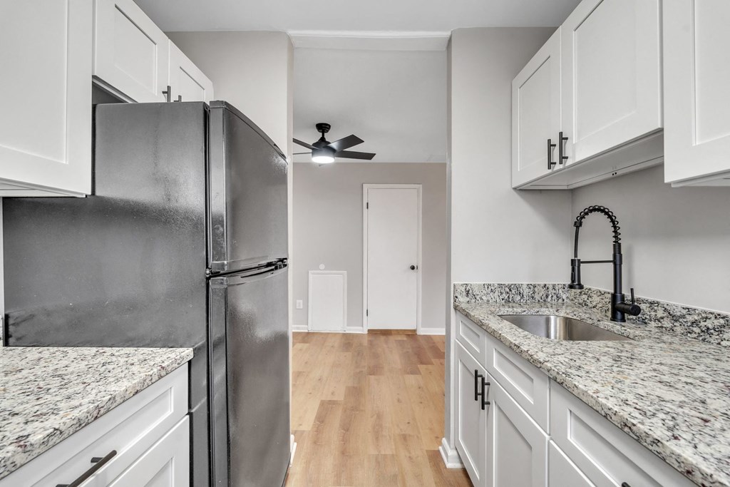 A kitchen with a black refrigerator and white cabinets.