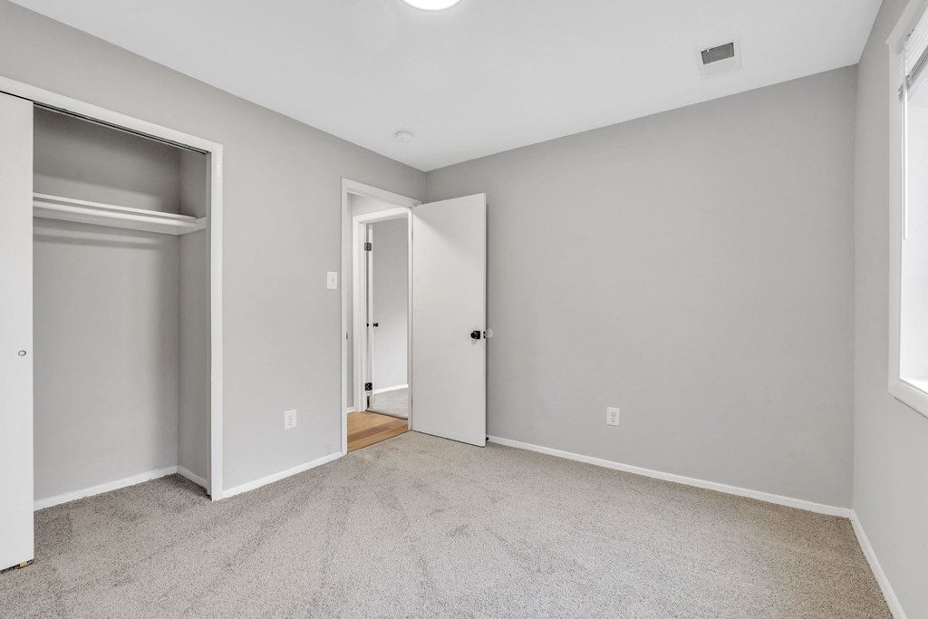 A room with a carpeted floor and a doorway leading to another room.