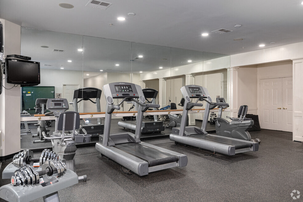 a gym with cardio equipment and a tv