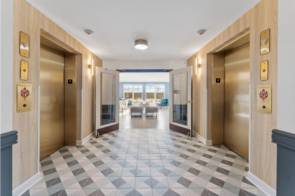 a hallway with elevators and doors and a checkered floor