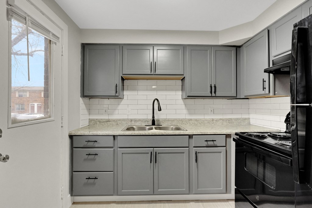 A kitchen with grey cabinets and a black stove.