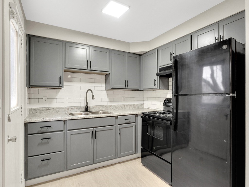 an empty kitchen with black appliances and gray cabinets