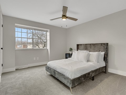 an empty bedroom with a bed and a ceiling fan