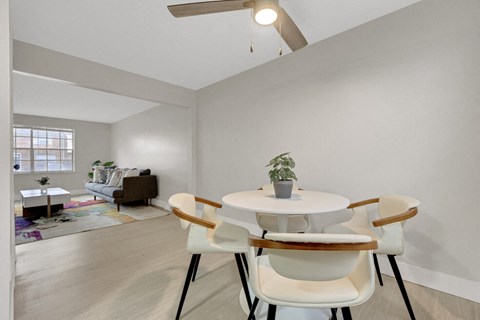 A white table with four chairs in a room with a ceiling fan.