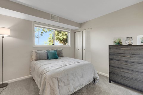 A bedroom with a bed, nightstand, and lamp.