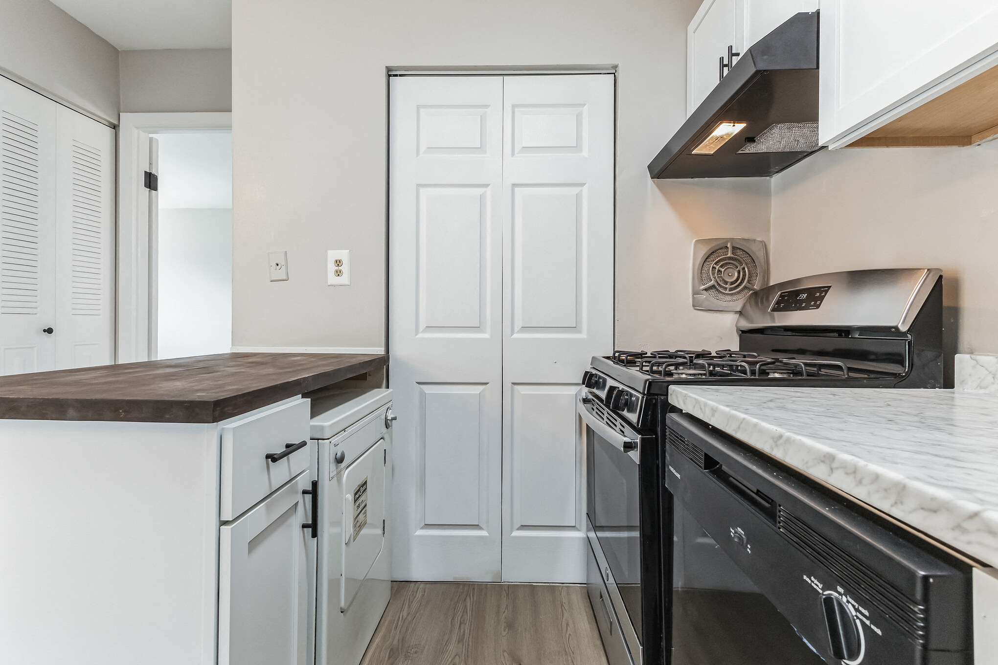 a kitchen with white cabinets and stainless steel appliances and a black stove