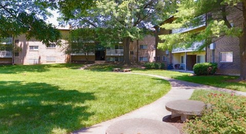 A sunny day at the park with a bench and a walking path.