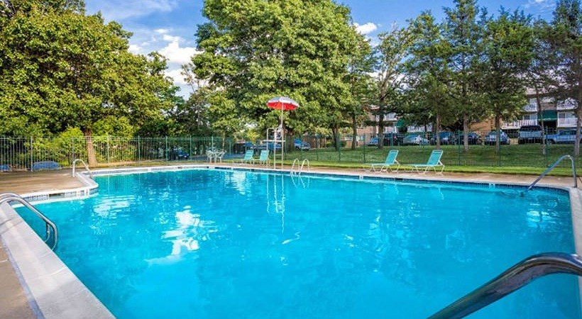 A swimming pool surrounded by trees and a fence.