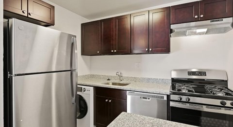 A kitchen with a stainless steel refrigerator, a stove, and a washing machine.
