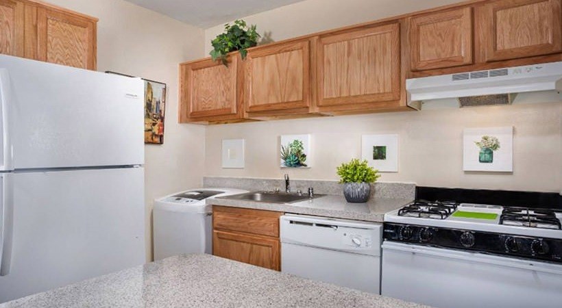 A kitchen with a white refrigerator, a white dishwasher, and a black stove top oven.