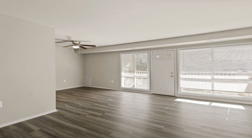 A room with a ceiling fan and sliding glass doors.