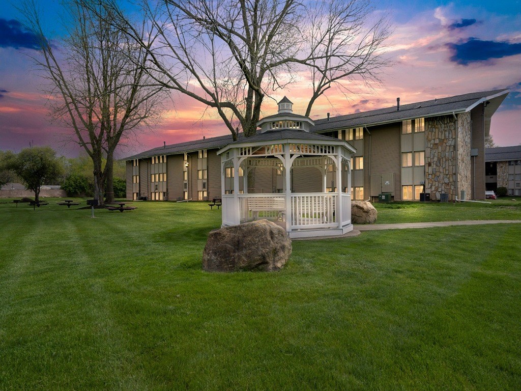 a gazebo in front of a building with a sunset in the background