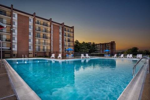 A large swimming pool in front of a multi-story apartment building.