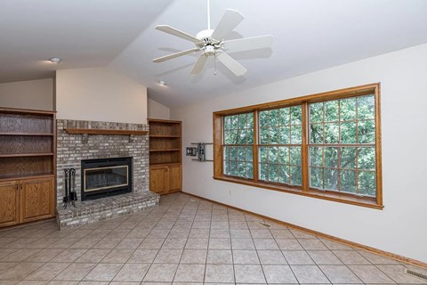 A living room with a fireplace and a ceiling fan.