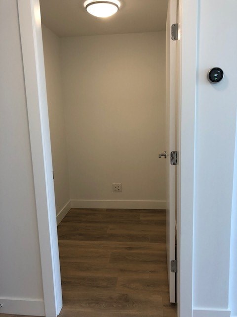 A white door with a black knob is on the right side of a hallway with wooden floors.