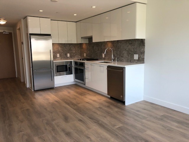 A kitchen with a refrigerator, microwave, oven, and sink.