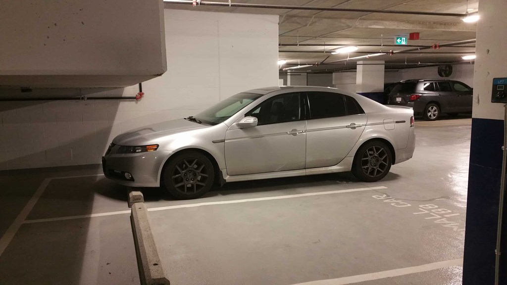 A silver car is parked in a dimly lit parking garage.