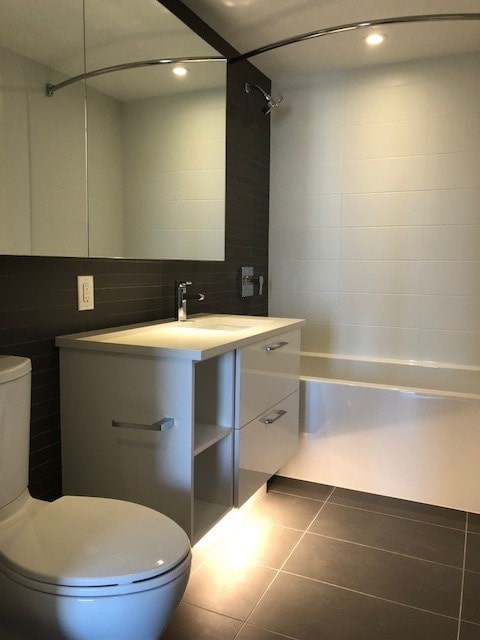 A bathroom with a toilet, sink, and mirror.