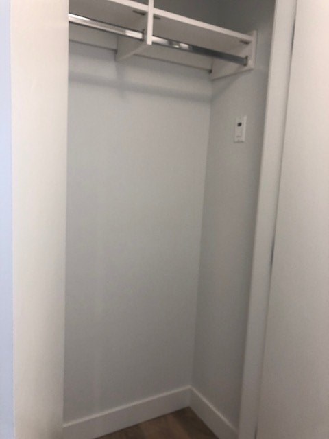 A white closet with a shelf and a light switch.