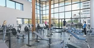 A gym with people working out and a view of the city outside the windows.