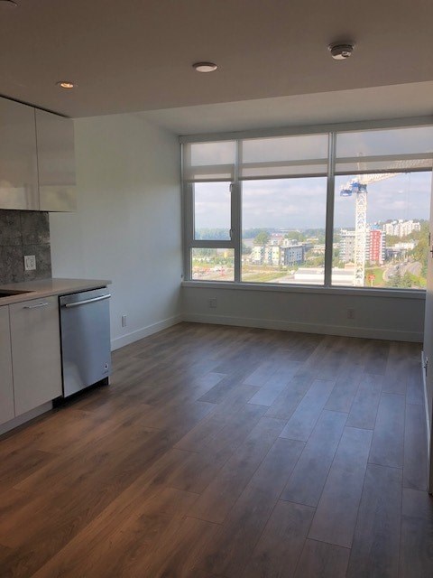 A kitchen with wooden floors and a large window overlooking a cityscape.
