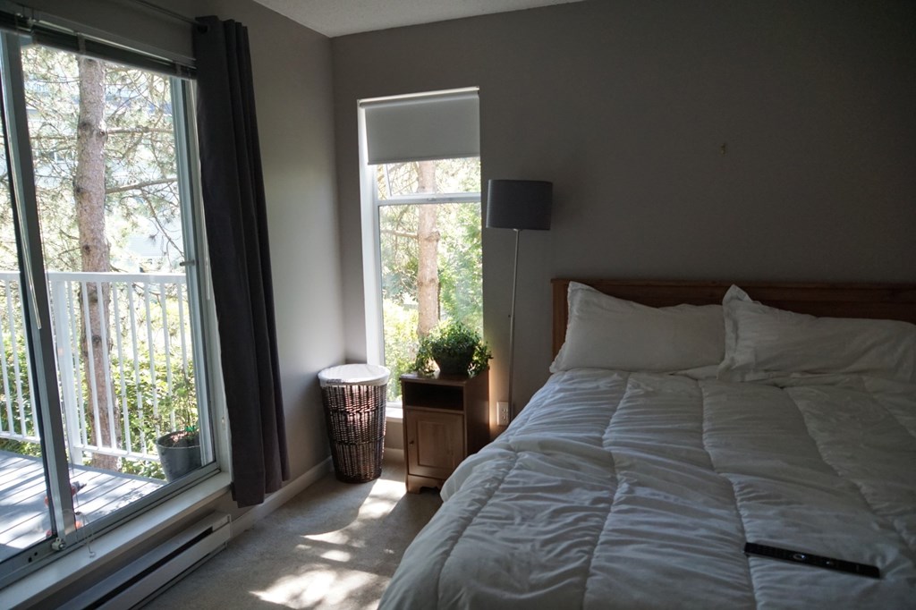 A bedroom with a large bed and a window overlooking a tree.