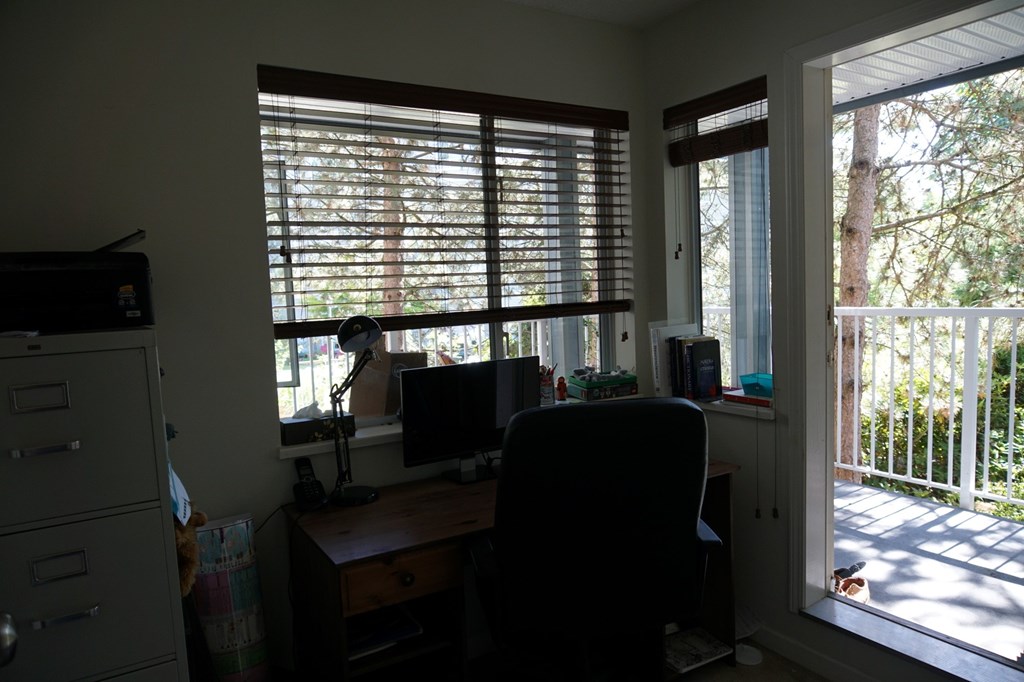 A room with a desk, chair, and a window with blinds.