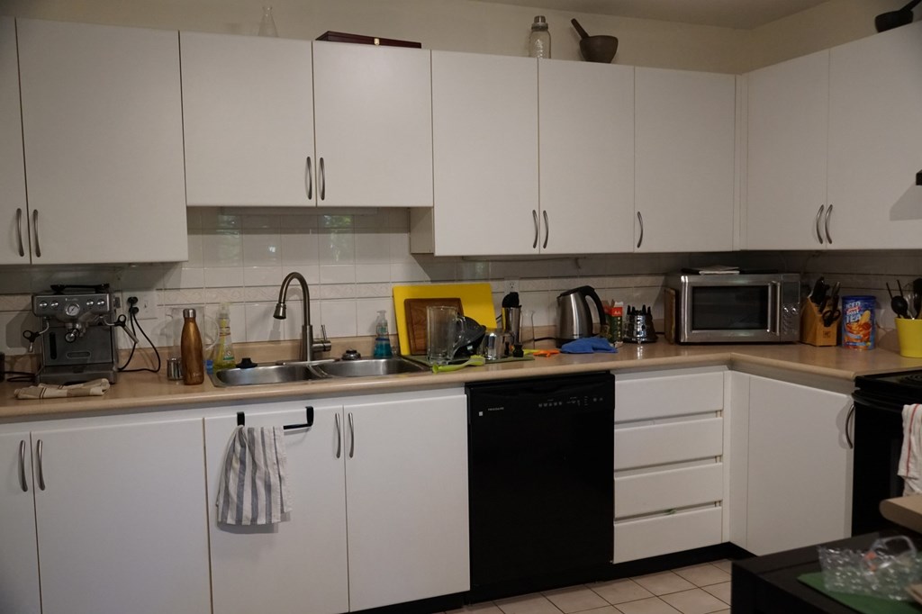 A kitchen with white cabinets and a black dishwasher.