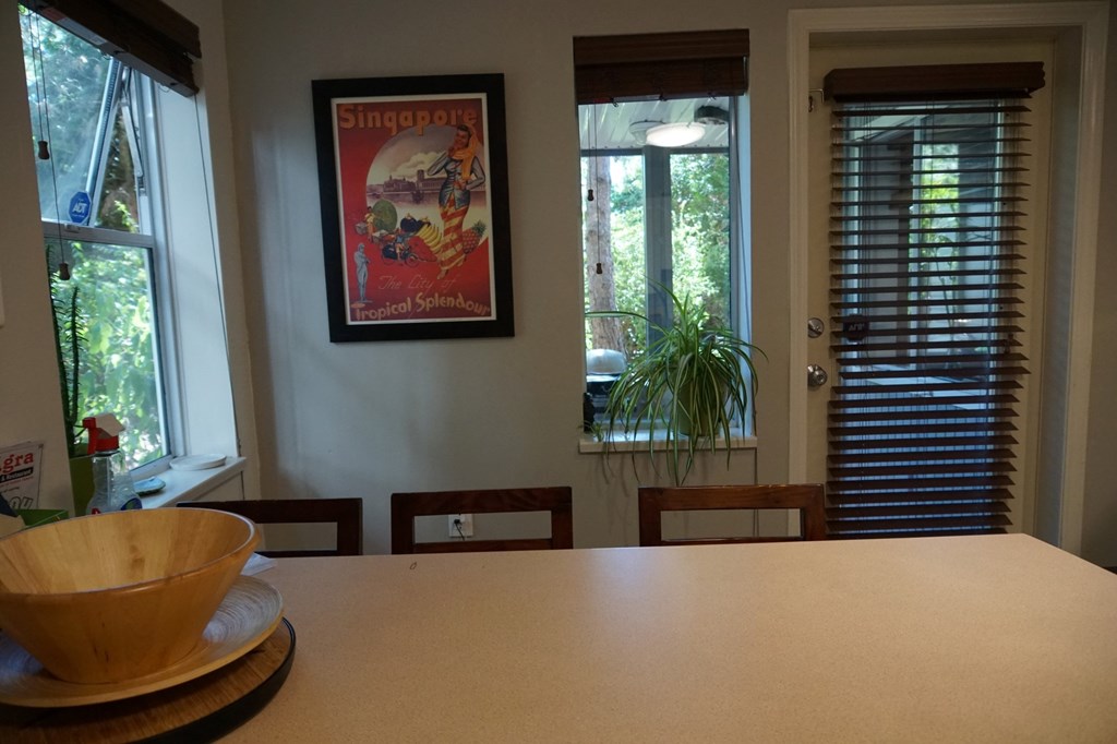 A dining room with a wooden table and a poster on the wall.