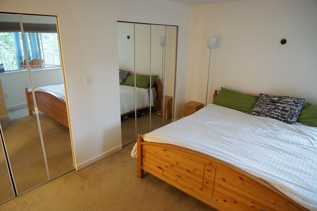 A bedroom with a bed, nightstand, and sliding glass doors.