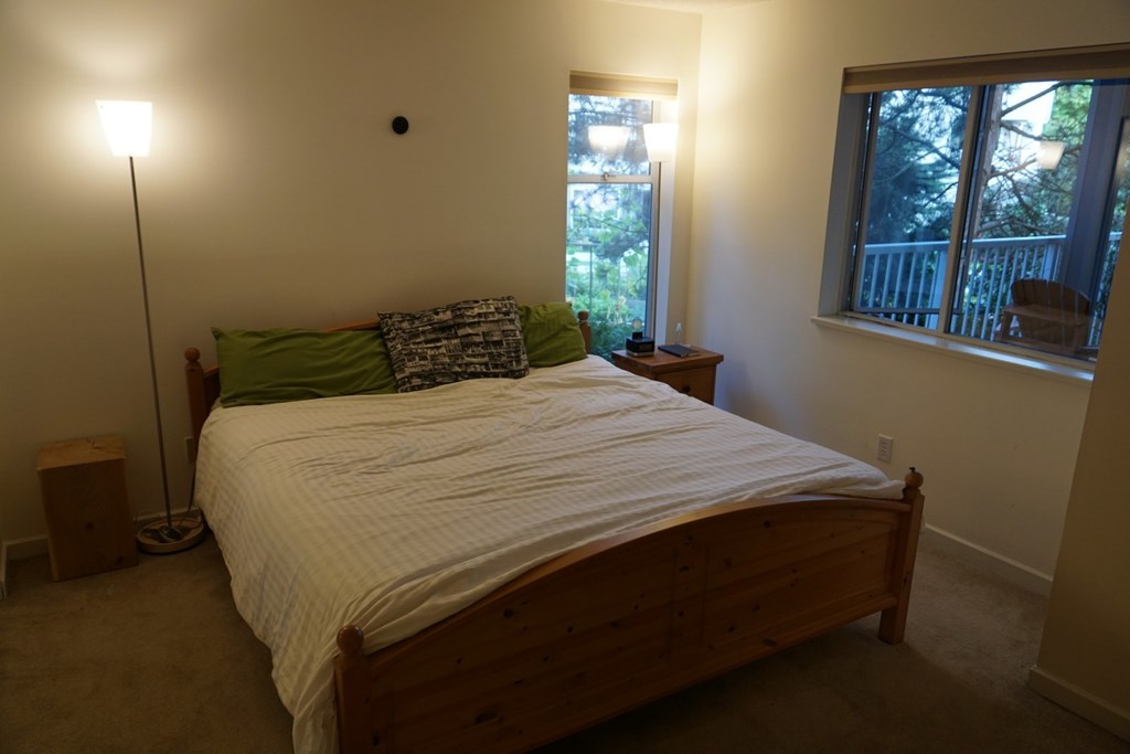 A bedroom with a bed, nightstand, and window.