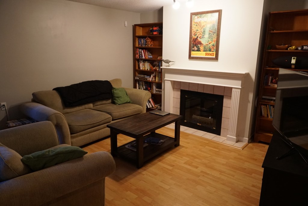 A living room with a fireplace and a painting on the wall.