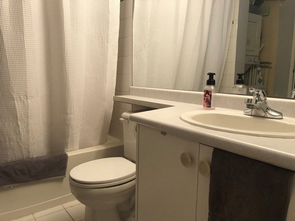 A bathroom with a toilet, sink, and shower curtain.
