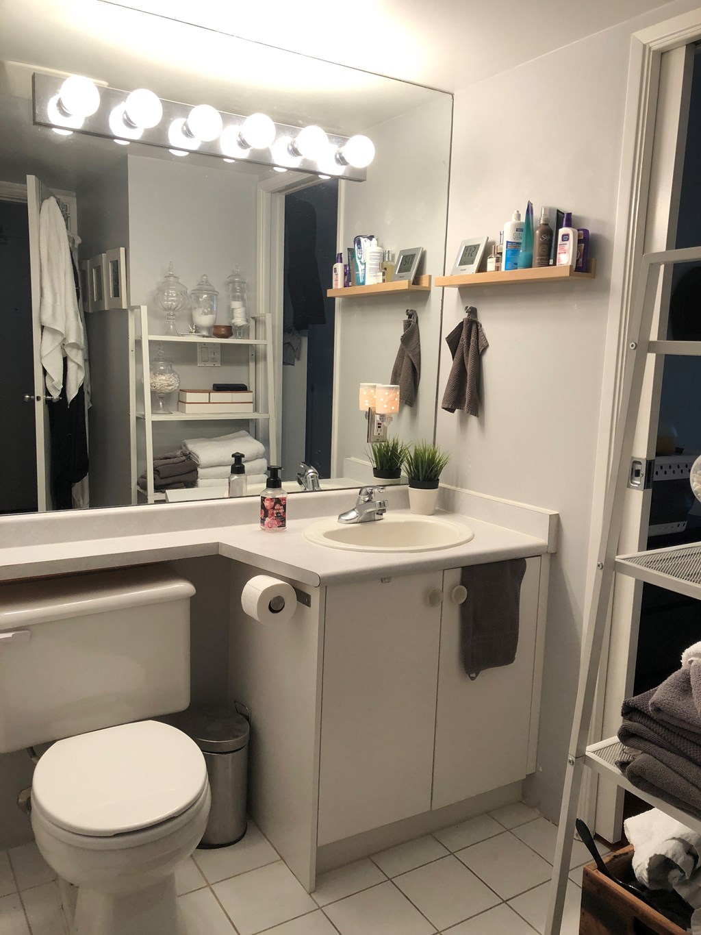 A white toilet is in a bathroom with a sink and mirror.