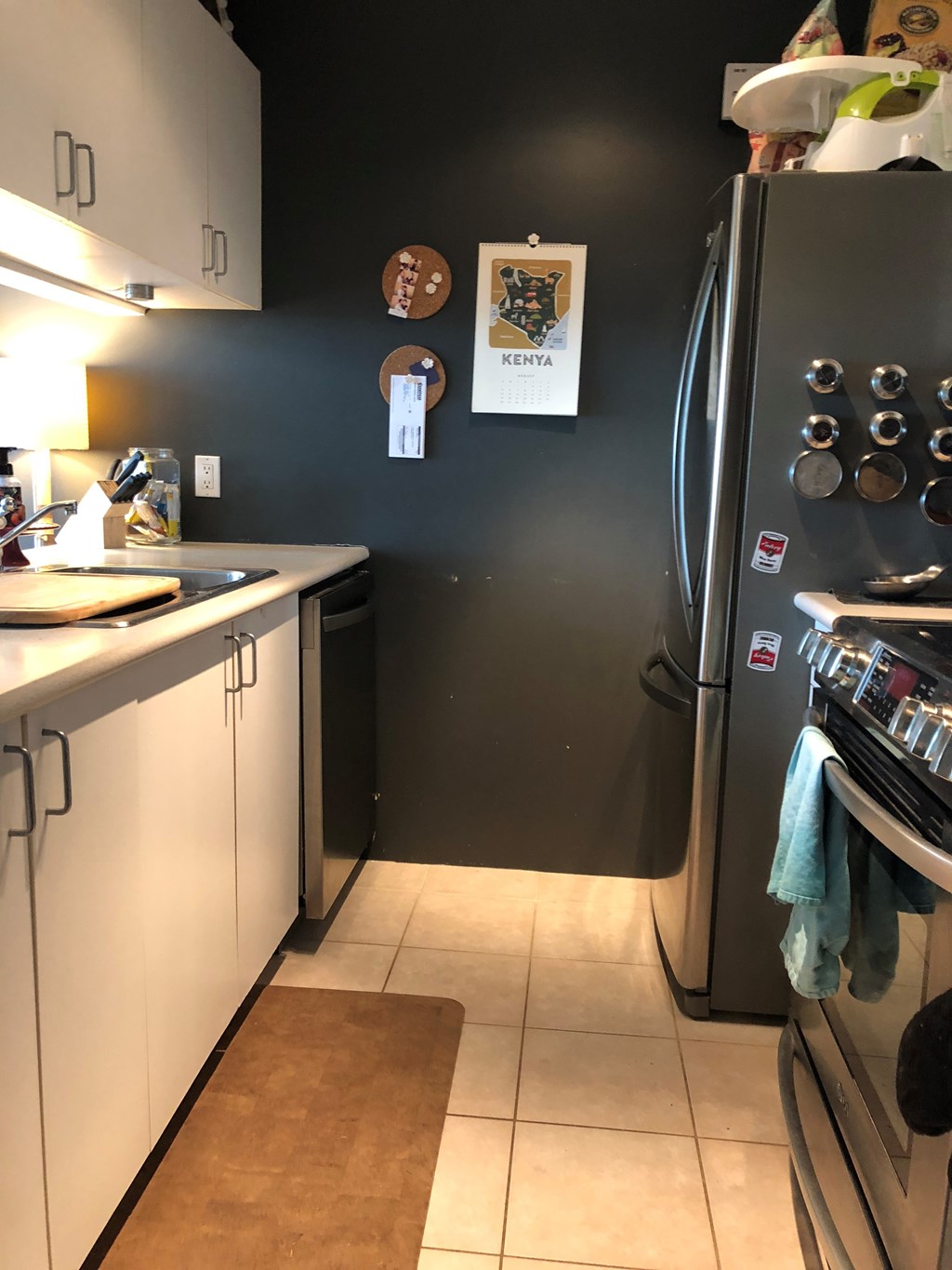 A kitchen with a black wall and a fridge with a blue towel hanging on it.